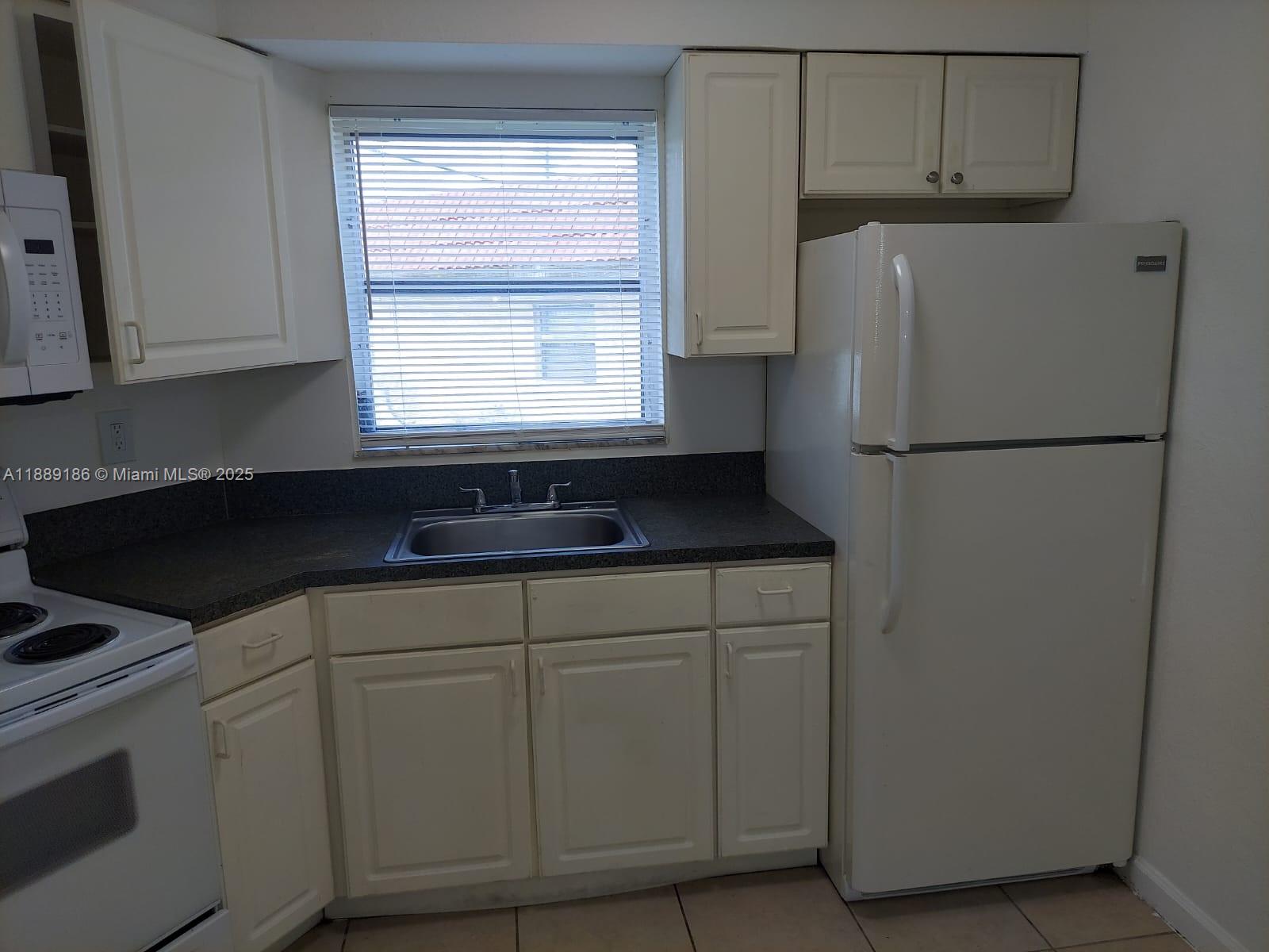 978 Southwest 10th Drive, Unit 9 Pompano Beach, FL 33060 - Photo 8 of 13 a kitchen with a refrigerator sink and cabinets