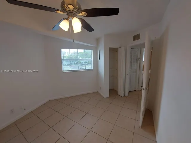 an empty room with windows and chandelier fan