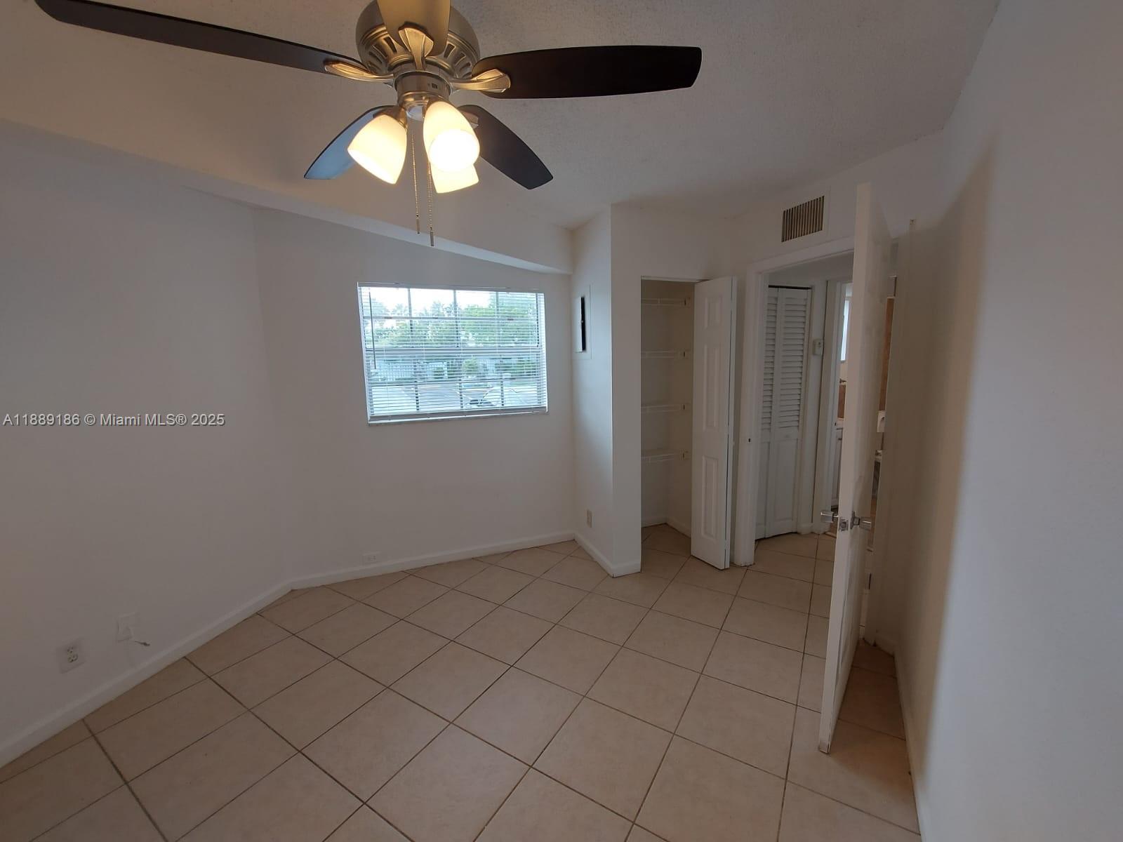 978 Southwest 10th Drive, Unit 9 Pompano Beach, FL 33060 - Photo 10 of 13 an empty room with windows and chandelier fan