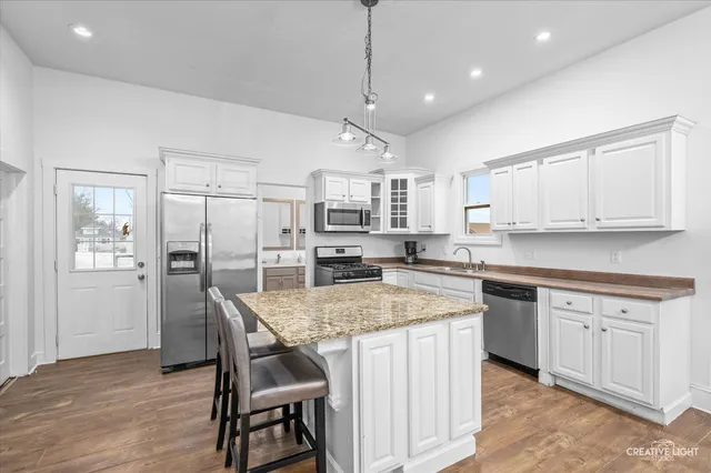 a kitchen with stainless steel appliances granite countertop a kitchen island hardwood floor and a sink