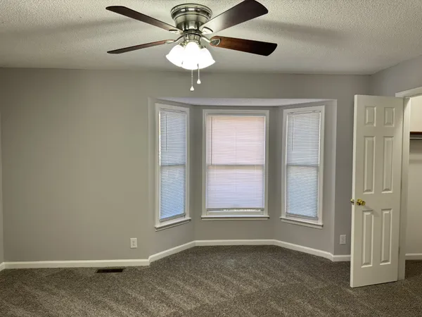 an empty room with windows and fan