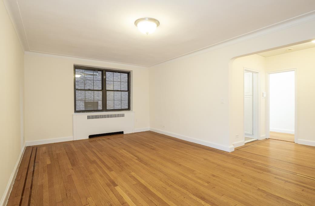 an empty room with wooden floor cabinet and windows