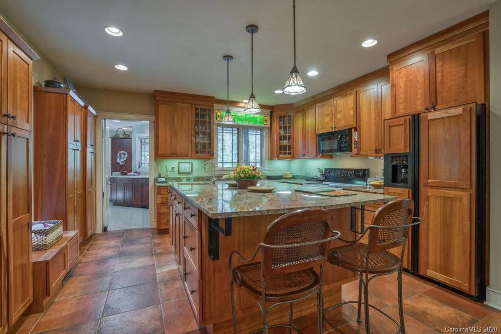 305 Misty Hill Road Columbus, NC 28722 - Photo 11 of 46 a kitchen with kitchen island granite countertop wooden cabinets and refrigerator