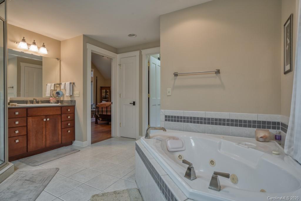 305 Misty Hill Road Columbus, NC 28722 - Photo 30 of 46 a bathroom with a tub a sink and a large mirror
