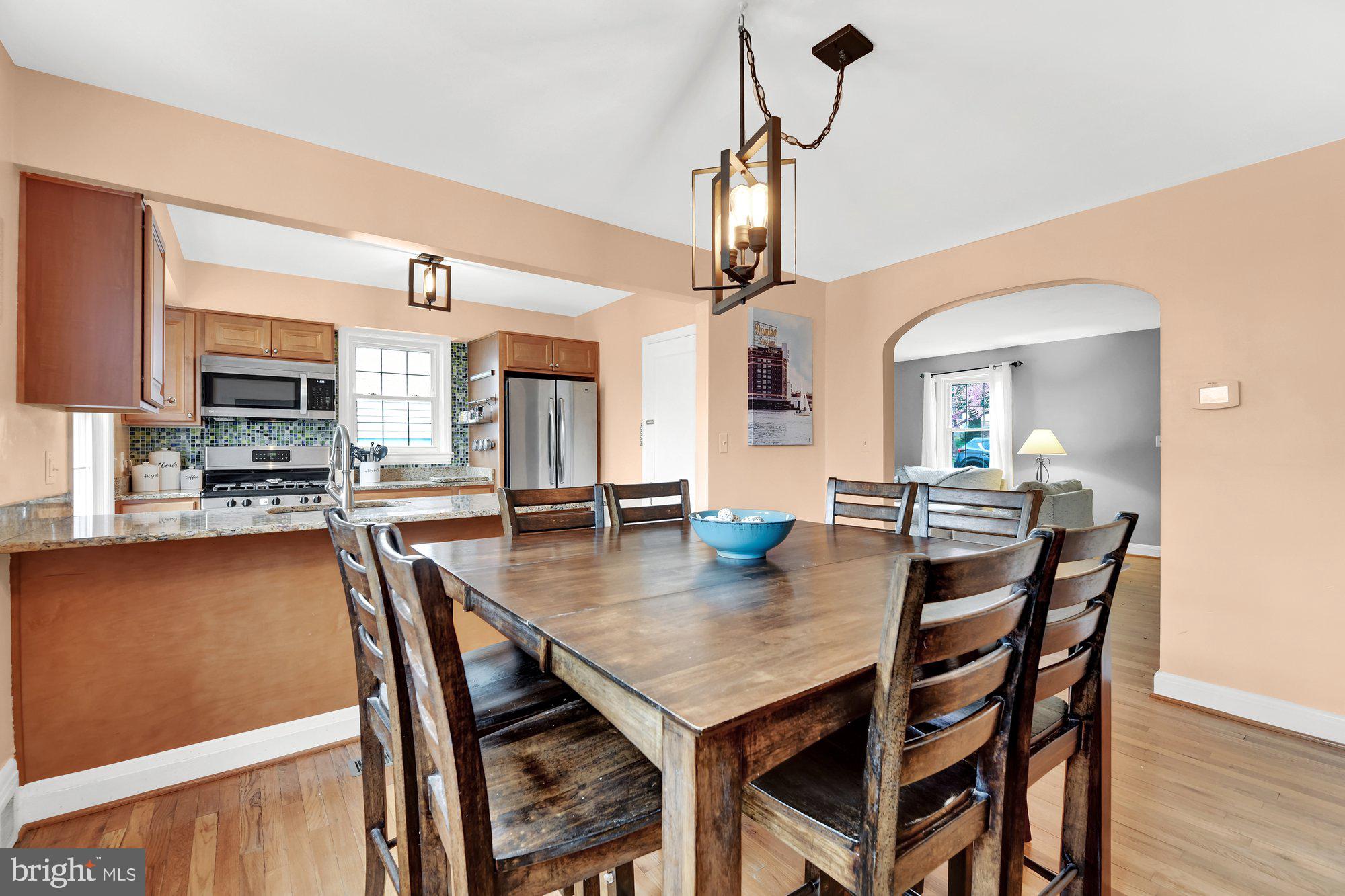 1107 Arran Road Baltimore, MD 21239 - Photo 13 of 29 a view of a dining room and livingroom with furniture wooden floor a rug a fireplace