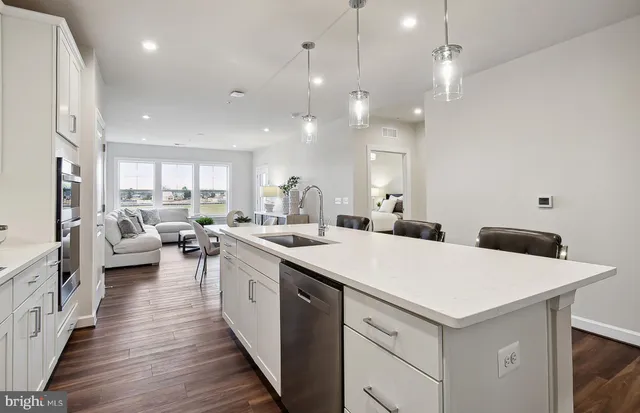a kitchen with counter top space a sink appliances and living room view