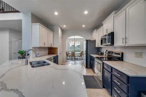 a kitchen with stainless steel appliances granite countertop a stove a sink a refrigerator and white cabinets