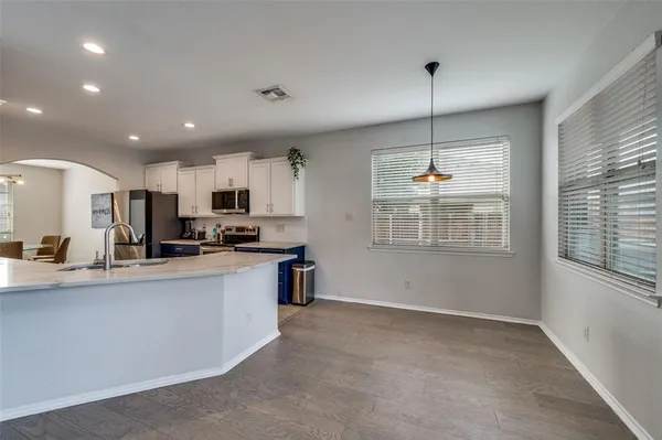 a kitchen with stainless steel appliances granite countertop a sink a stove a refrigerator cabinets and a window