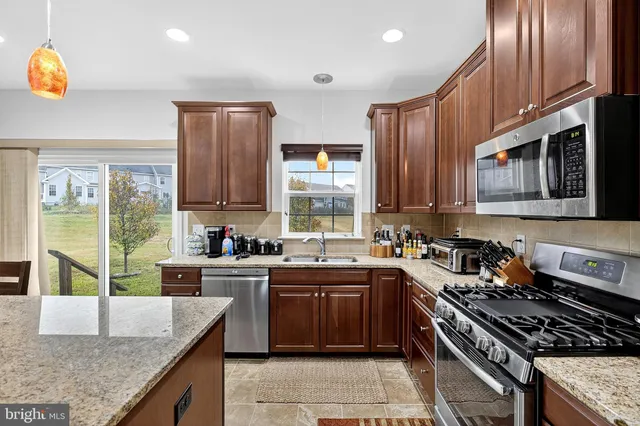 a kitchen with kitchen island granite countertop stainless steel appliances and wooden cabinets