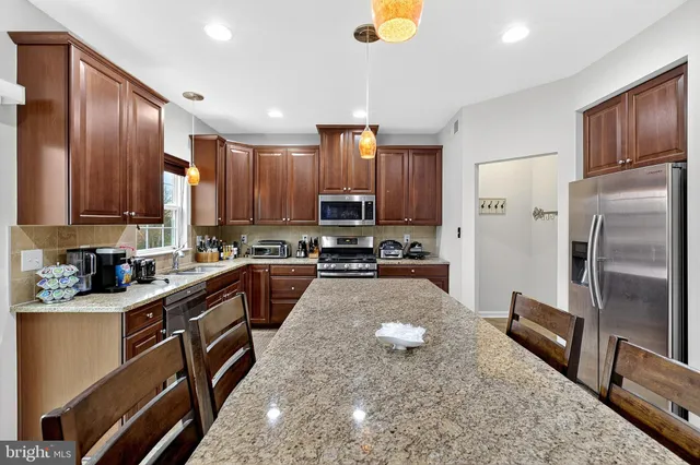 a kitchen with stainless steel appliances granite countertop a refrigerator a stove and a sink