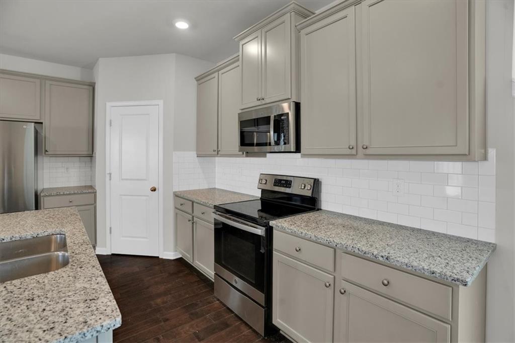 1506 Ashbrooke Trace Stone Mountain, GA 30083 - Photo 6 of 54 a kitchen with granite countertop white cabinets and stainless steel appliances