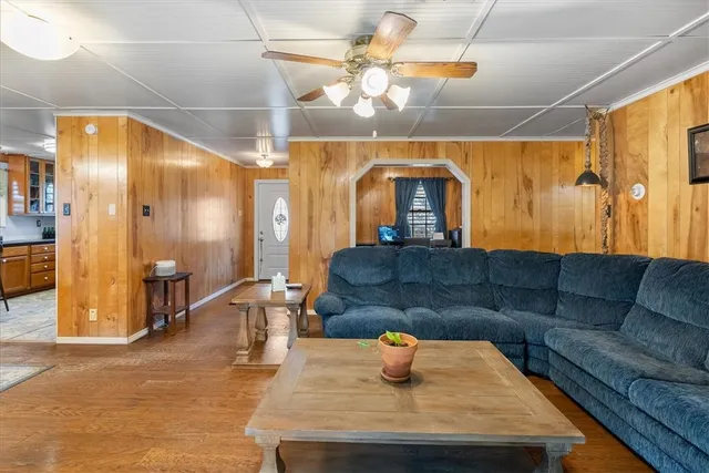 a living room with stainless steel appliances furniture a chandelier a kitchen view and a large window