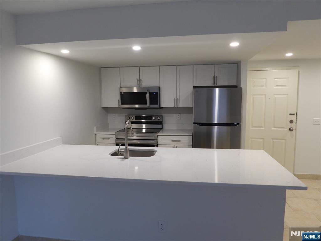 55 Clinton Place, Unit 301 Hackensack, NJ 07601 - Photo 9 of 17 a kitchen with a refrigerator a stove and a sink