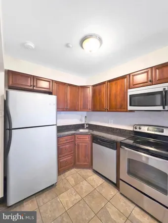a kitchen with stainless steel appliances granite countertop a refrigerator sink and white cabinets