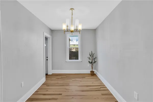 a view of a hallway with wooden floor and a chandelier