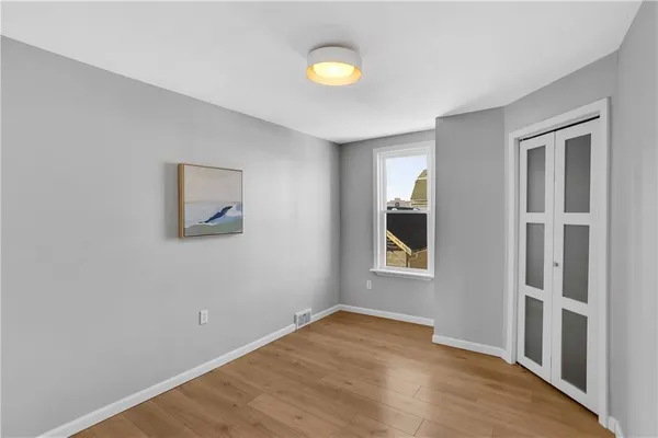 a view of an empty room with wooden floor and window