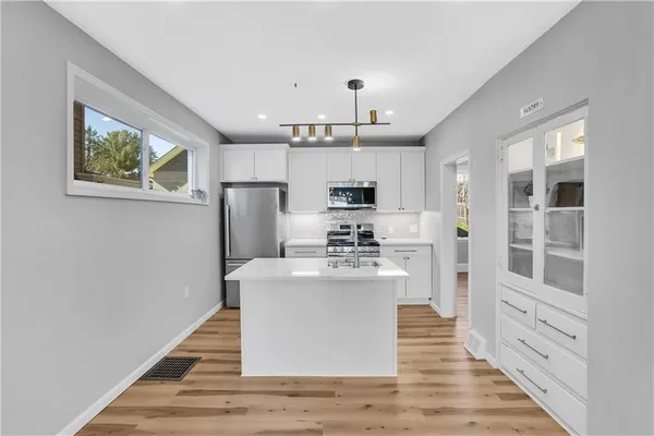 a living room with stainless steel appliances kitchen island granite countertop a stove and a refrigerator