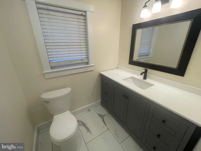 a bathroom with a toilet sink vanity and mirror