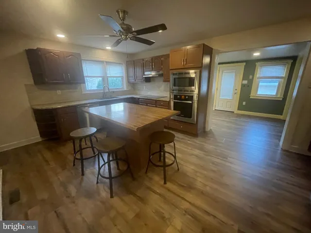 a kitchen with stainless steel appliances kitchen island granite countertop a table chairs and a refrigerator