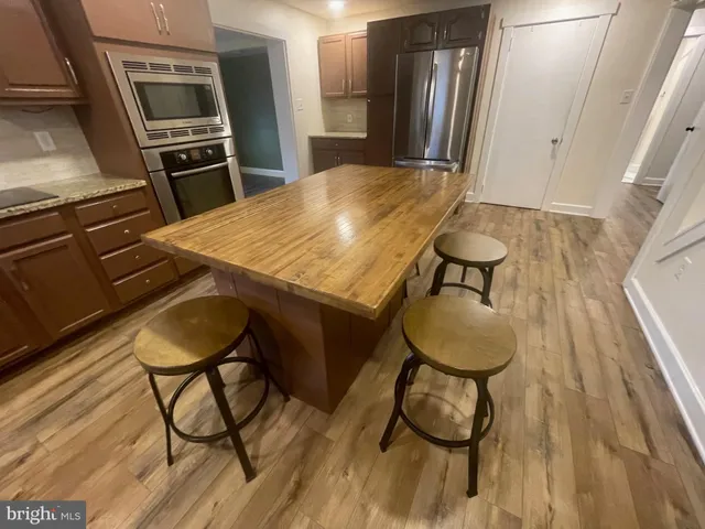 a kitchen with granite countertop a table chairs stove and refrigerator