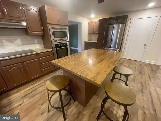 a kitchen with stainless steel appliances granite countertop a refrigerator a stove a sink and chairs