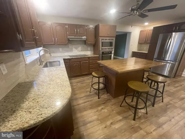 a kitchen with stainless steel appliances granite countertop table chairs sink and cabinets