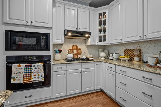 a kitchen with granite countertop white cabinets and stainless steel appliances