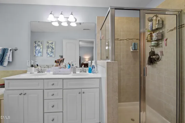 a bathroom with a double vanity sink mirror and shower