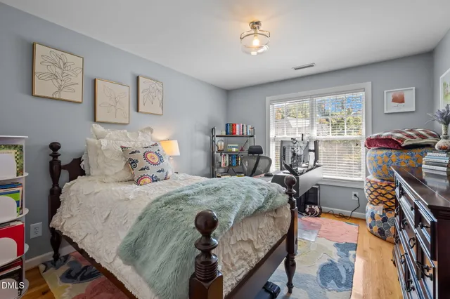 a bedroom with bed and a large mirror on the dresser