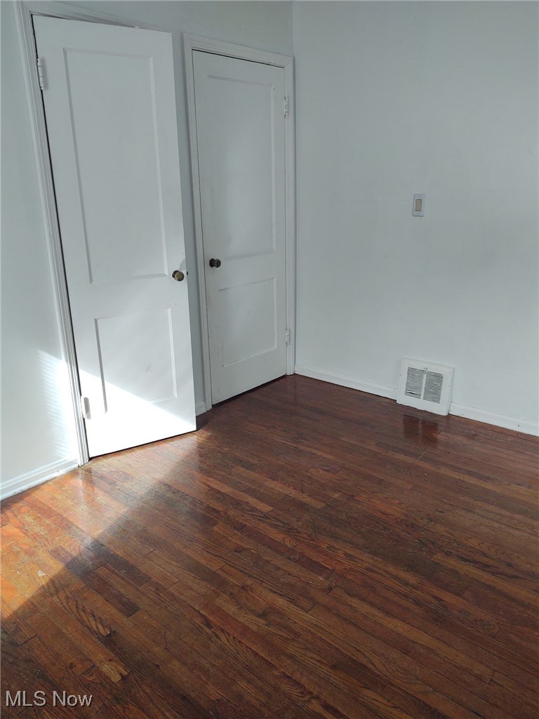 21216 Watson Road Maple Heights, OH 44137 - Photo 4 of 6 Unfurnished room with baseboards, visible vents, and dark wood finished floors