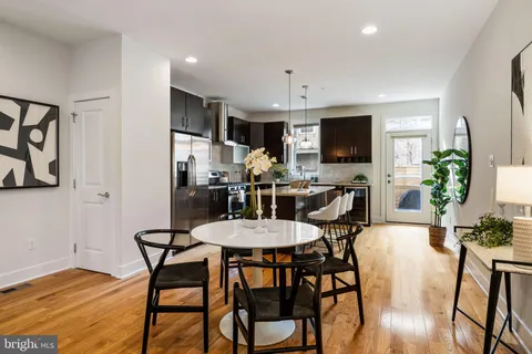 a kitchen with stainless steel appliances granite countertop a refrigerator a stove a sink a dining table and chairs