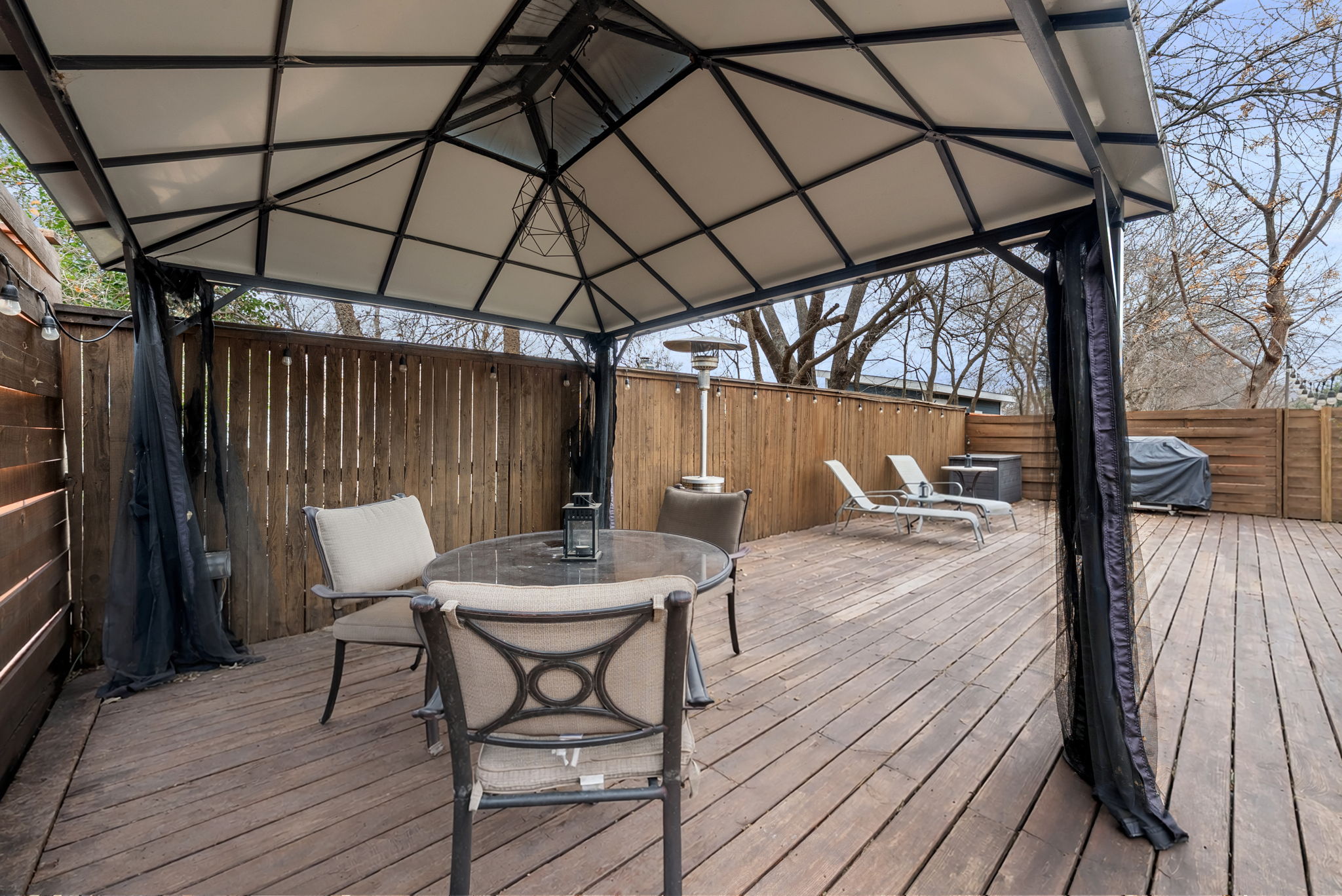 1501 Homespun Road Austin, TX 78745 - Photo 30 of 33 Wooden deck with outdoor dining space, a fenced backyard, a gazebo, and a grill