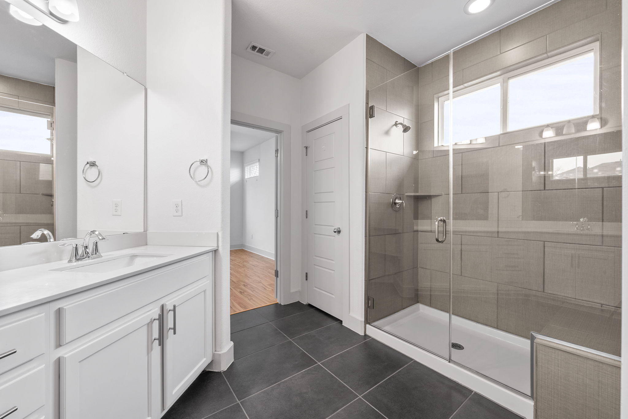 1501 Homespun Road Austin, TX 78745 - Photo 6 of 33 Bathroom featuring a shower stall, vanity, and dark tile patterned flooring