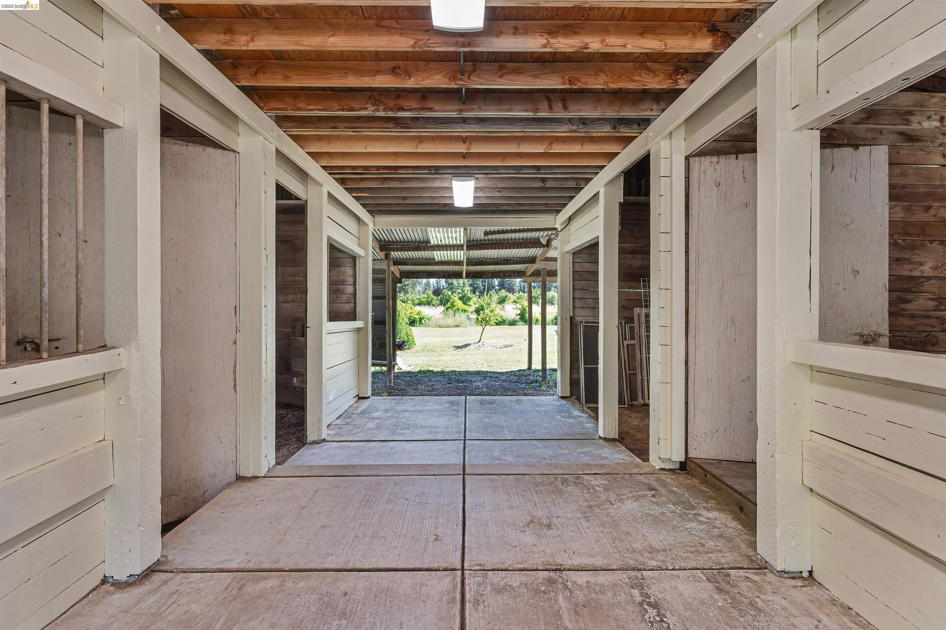 10474 Sheldon Road Elk Grove, CA 95624 - Photo 59 of 83 Barn interior featuring multiple stalls with wood-paneled walls and exposed wood beam ceiling