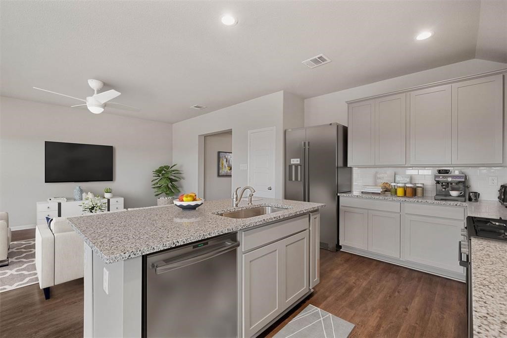 2103 Spring Hollow Drive Baytown, TX 77521 - Photo 11 of 27 a kitchen with stainless steel appliances granite countertop a sink a stove a refrigerator a microwave a dining table and chairs with wooden floor