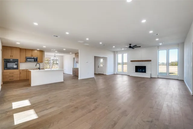 a view of an empty room with kitchen and fireplace