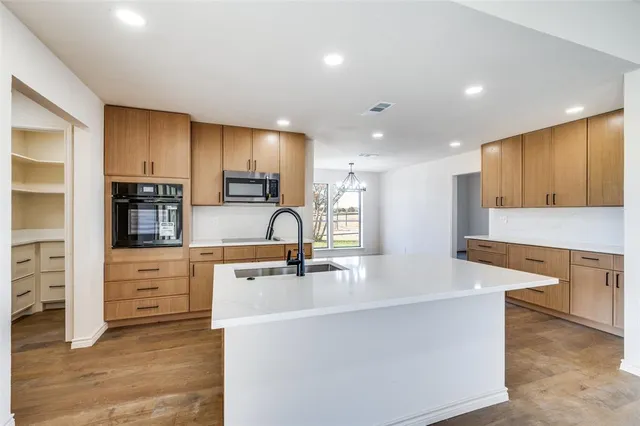 a large kitchen with stainless steel appliances granite countertop a sink a stove and a refrigerator