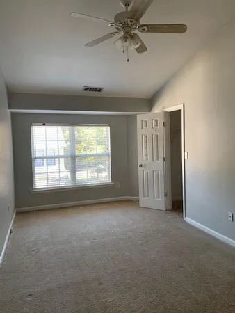en empty room with windows and chandelier fan
