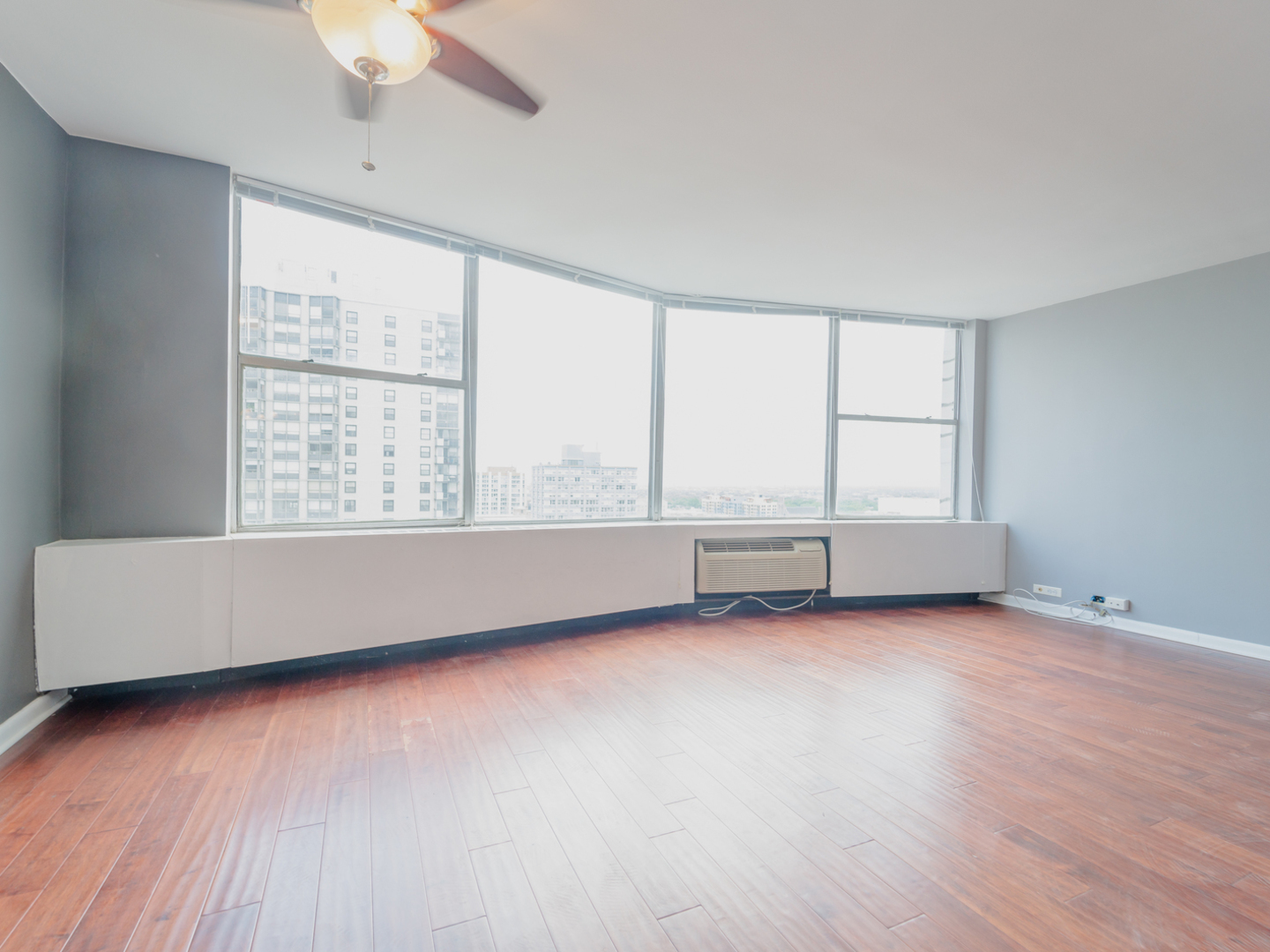 5757 North Sheridan Road, Unit 20F Chicago, IL 60660 - Photo 3 of 35 an empty room with wooden floor and windows with curtains