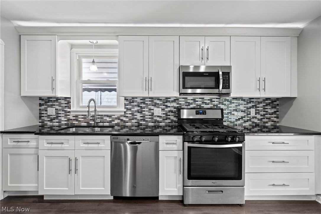 3261 Berea Road Cleveland, OH 44111 - Photo 20 of 43 White shaker-style cabinetry, dark countertops, mosaic tile backsplash, stainless steel appliances, and dark wood-finish flooring
