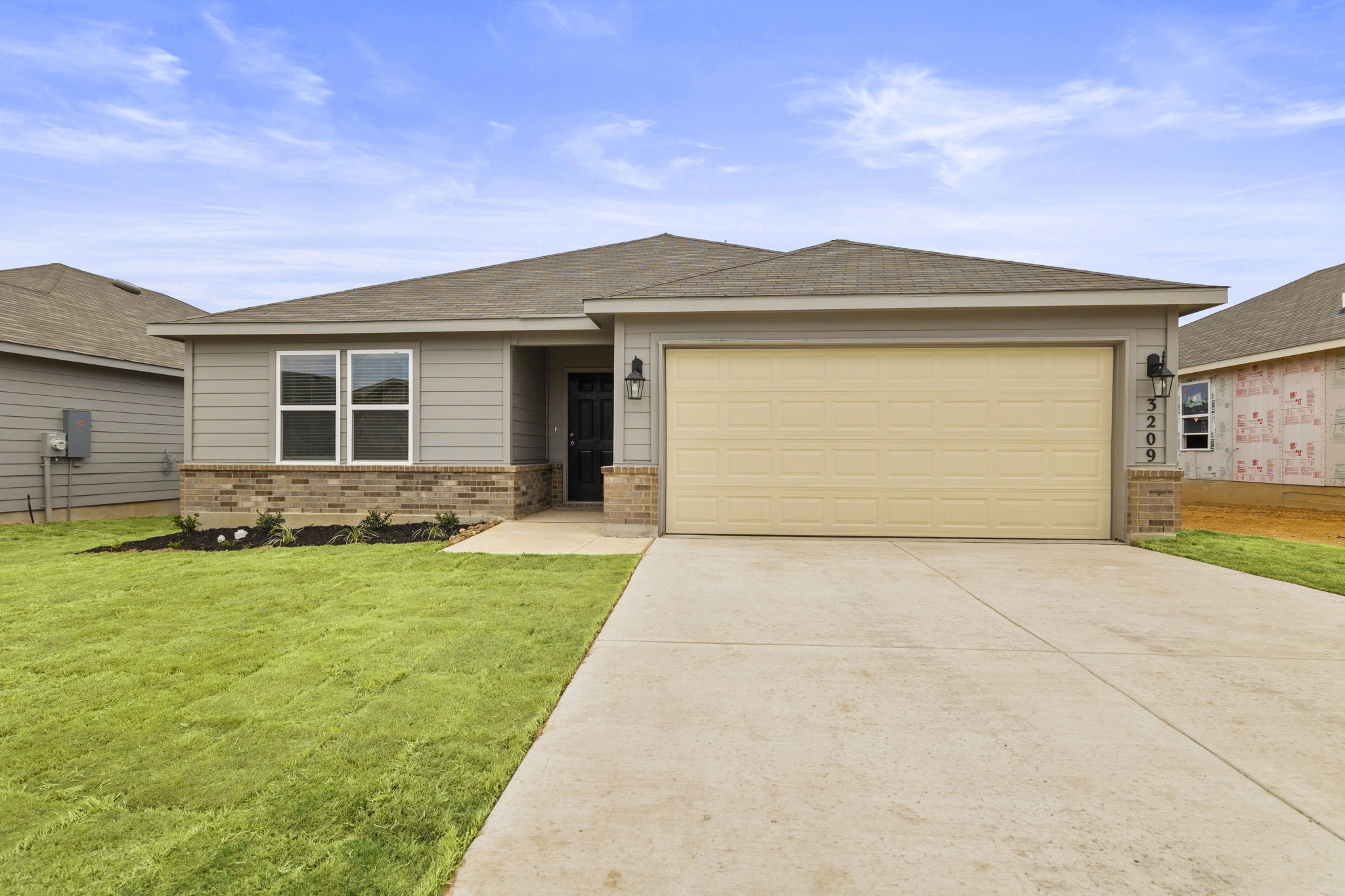 Ranch-style home with brick siding, driveway, a garage, roof with shingles, and a front yard