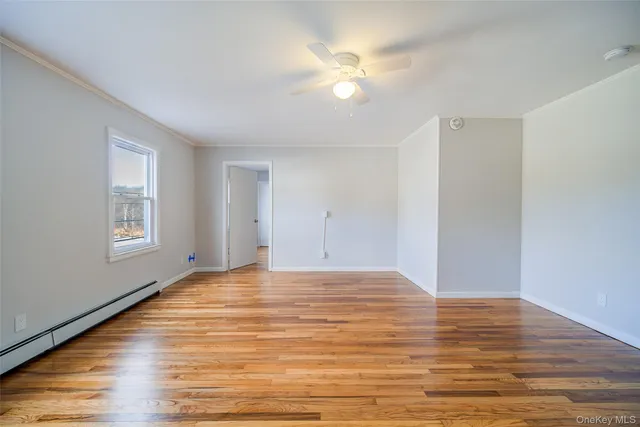 a view of an empty room with window and wooden floor