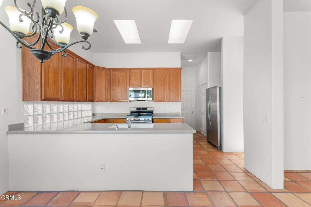 67 Tempe Trail Palm Desert, CA 92211 - Photo 15 of 56 a kitchen with stainless steel appliances a sink a stove a refrigerator cabinets and a dining table