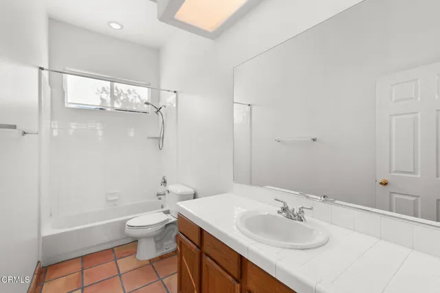a bathroom with a granite countertop sink a toilet and shower