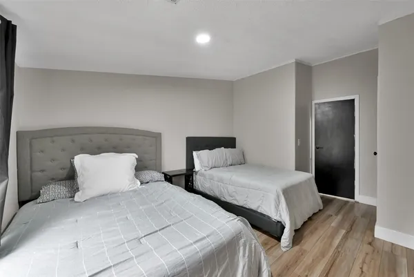 a bedroom with two beds and wooden floor