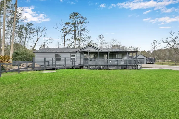 a view of a house with a big yard plants and large trees