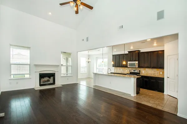 a kitchen with stainless steel appliances granite countertop a stove top oven a sink dishwasher and a fireplace with wooden floor