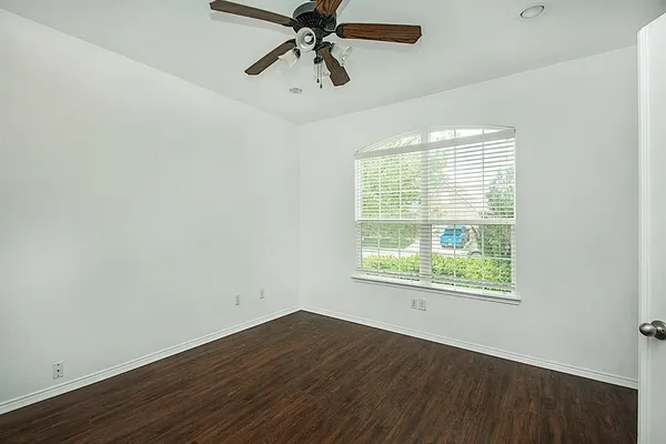 an empty room with wooden floor fan and windows