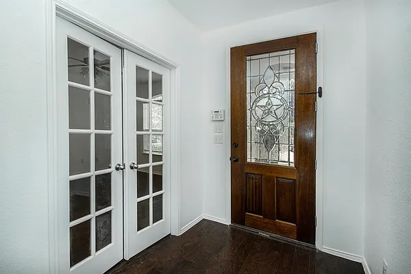 a view of an empty room with wooden floor and windows