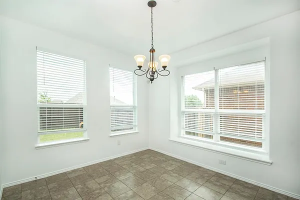 a view of an empty room with windows and chandelier